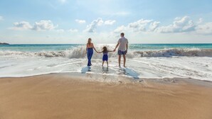 A family holding hands on a sandy beach with waves, under a clear sky. - Marina Inn Grande Dunes Condos & Suites (Myrtle Beach)