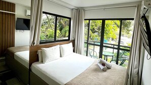A hotel room with a large bed, a TV, and a window with curtains. - Green Porto 104  (Ipojuca)