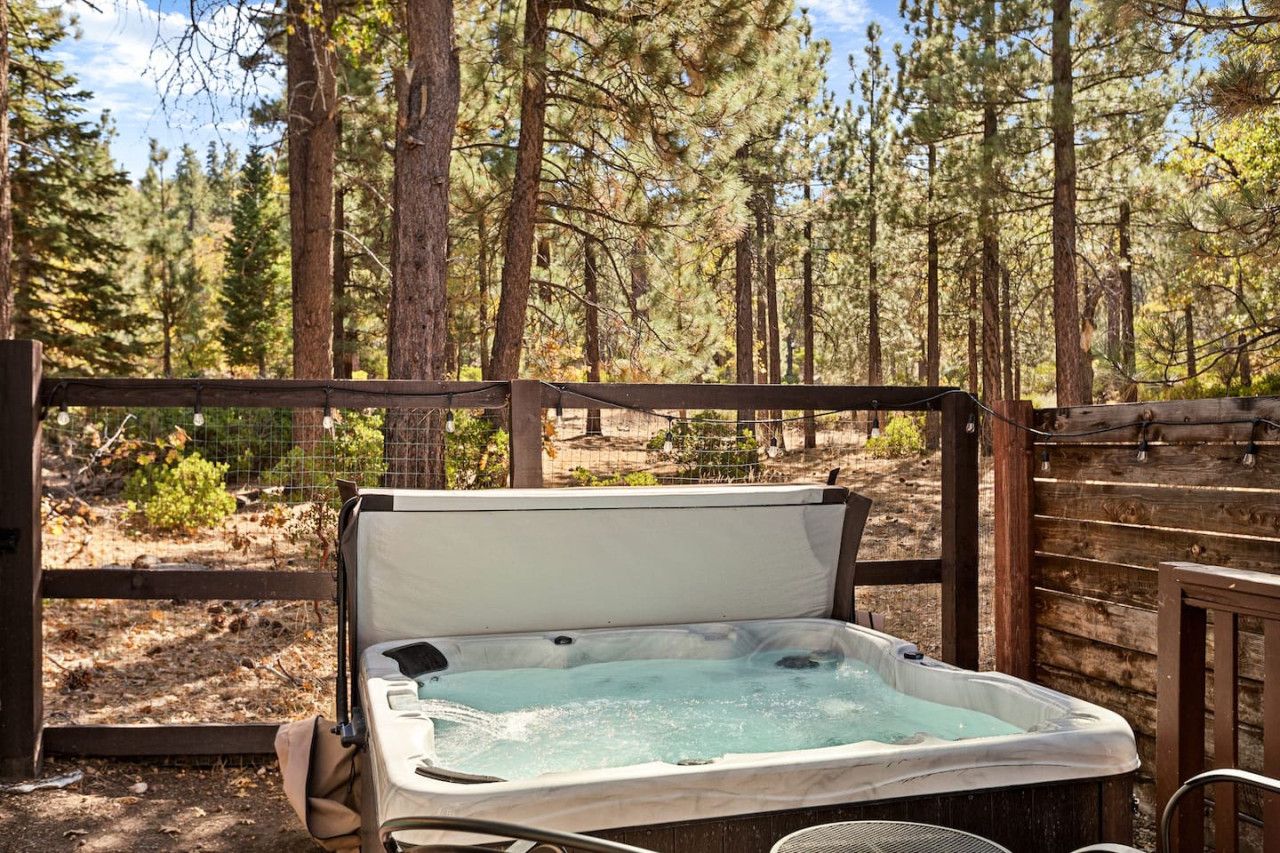 Un jacuzzi en un área boscosa con una terraza de madera y una cerca.