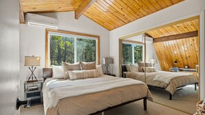 A bedroom with a large bed, two bedside tables, a mirror, and a view of the outdoors. - National Forest View Chalet: Hot Tub, A/C & BBQ (Big Bear Lake)