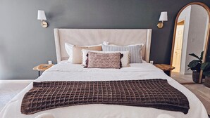 A neatly made bed with a textured blanket, multiple pillows, and a bedside table with a lamp.