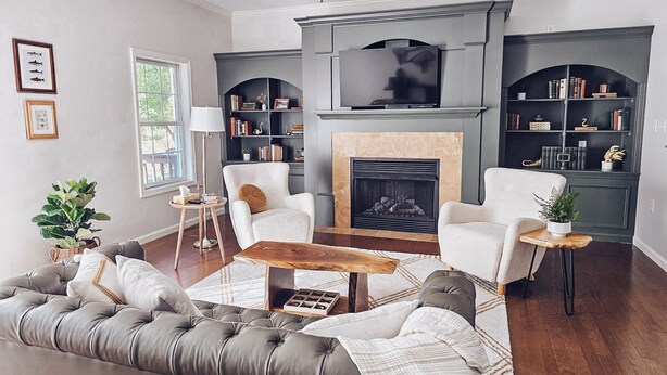 A modern living room with a fireplace, comfortable seating, and a bookshelf.
