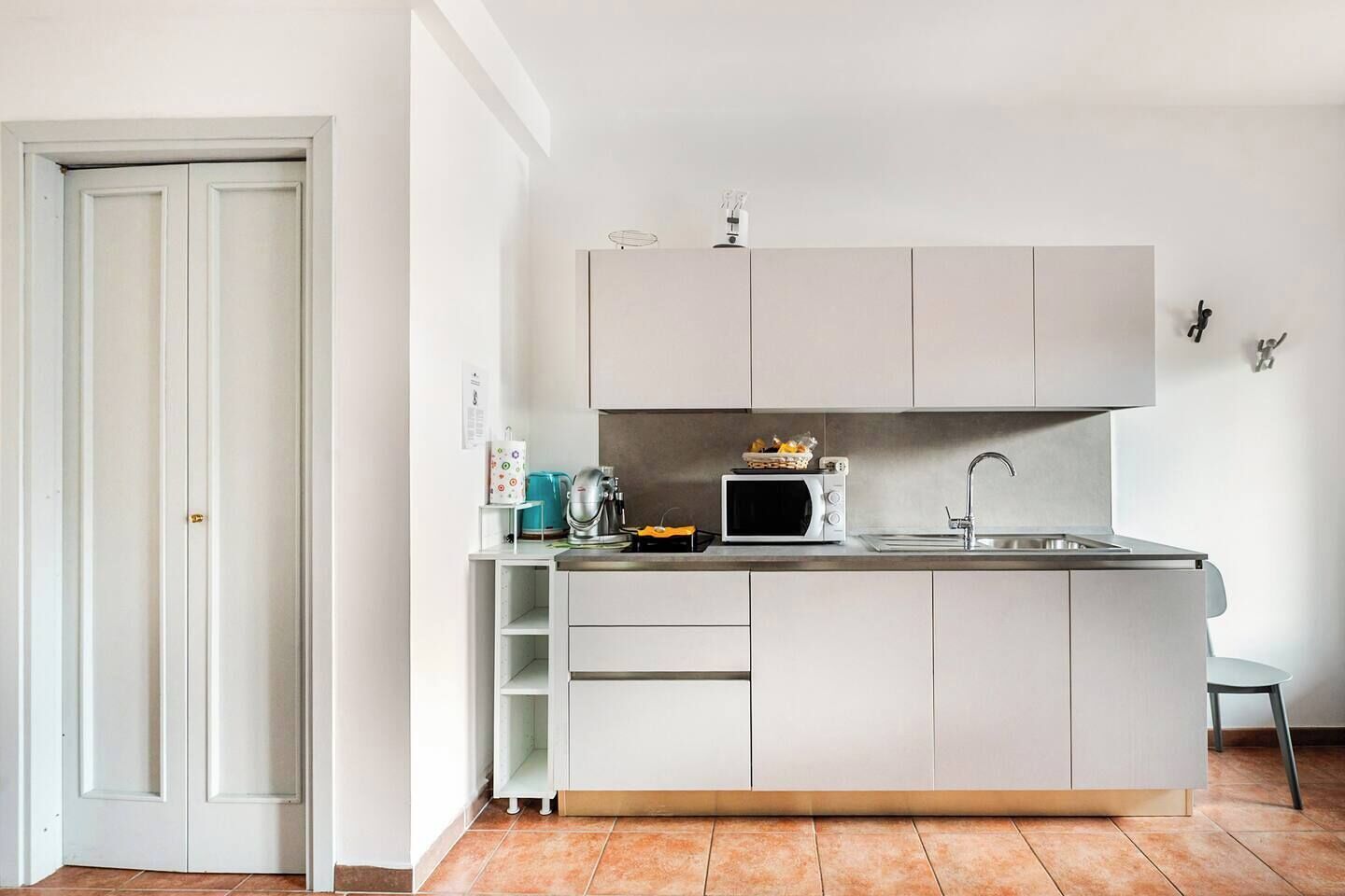 Eine kleine Küche mit Mikrowelle, Wasserkocher und Toaster auf der Arbeitsplatte sowie einem kleinen Spülbecken.