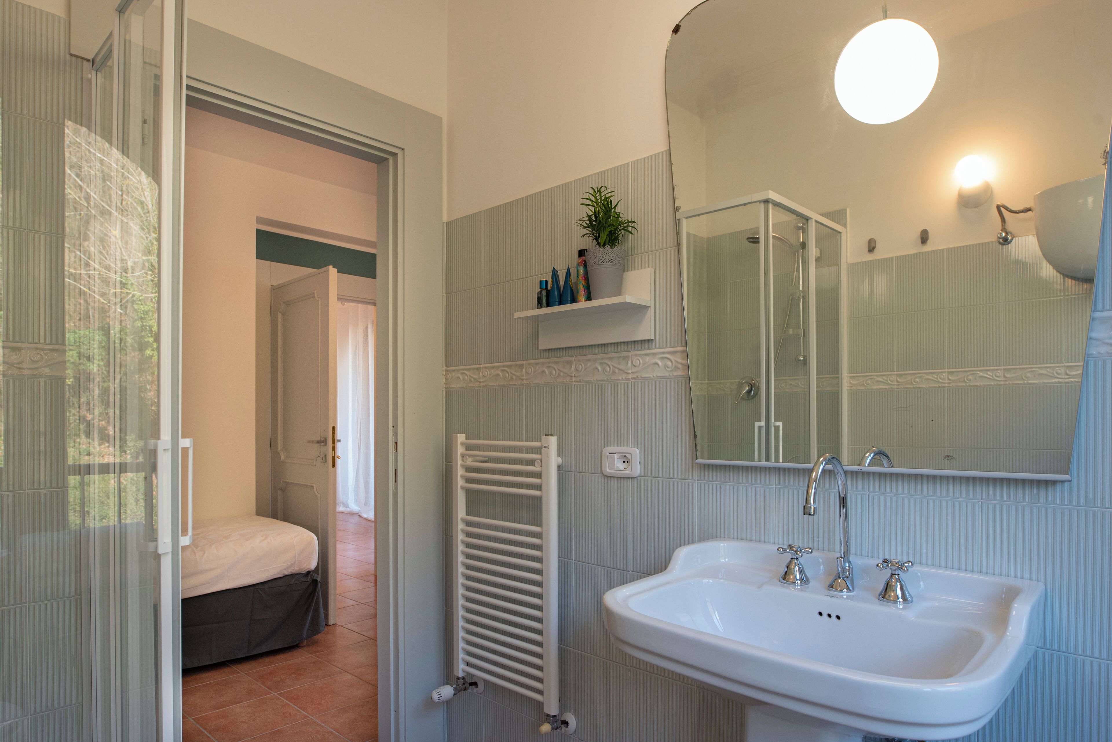Un baño con un lavabo blanco, un espejo, toallero y zona de ducha.