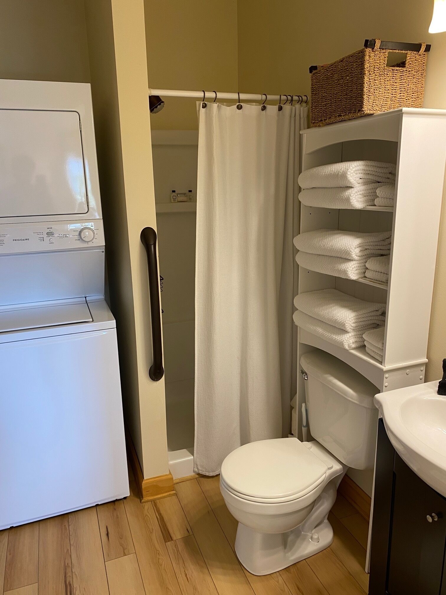 A compact bathroom with a white toilet, a white sink, and a white washing machine.