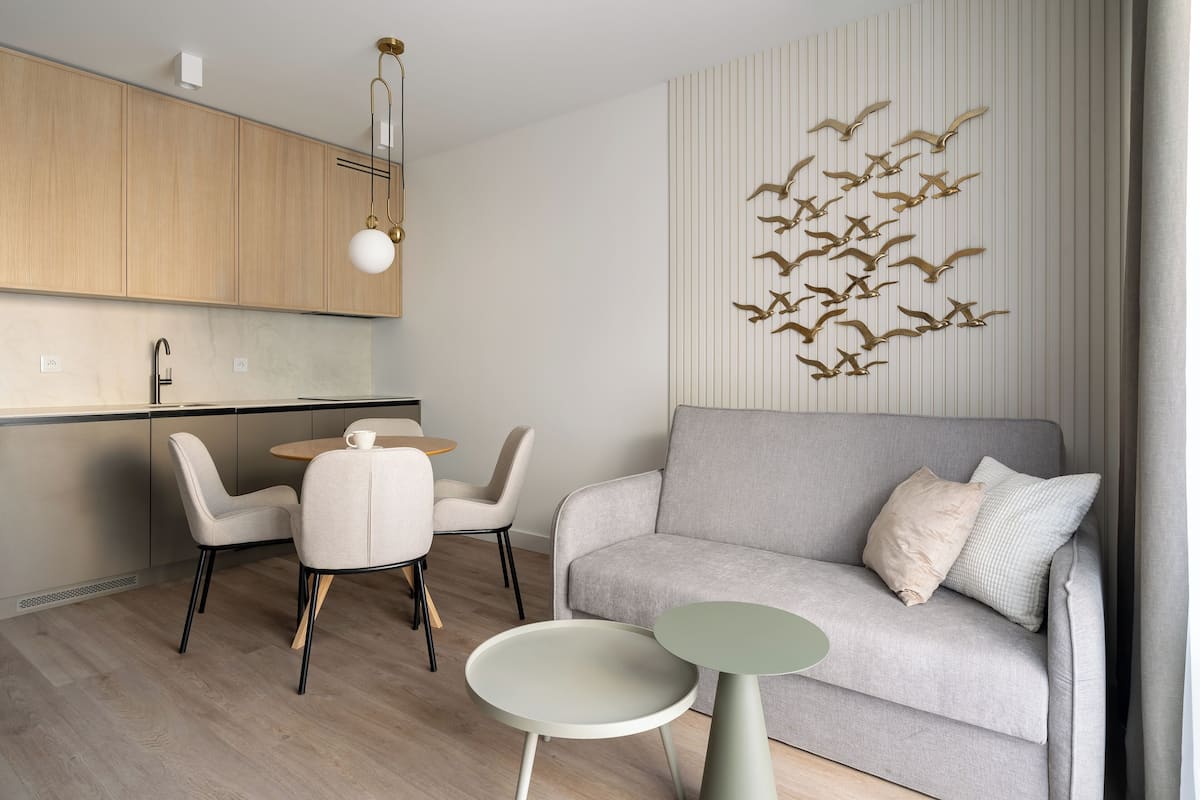 A modern living room with a grey sofa, a dining table with chairs, and a small side table.