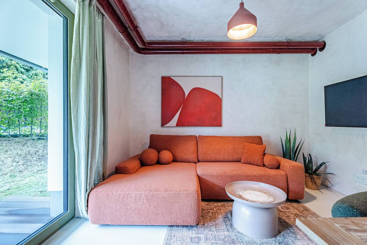 A modern living room with a sectional sofa, a coffee table, and a large window with curtains.