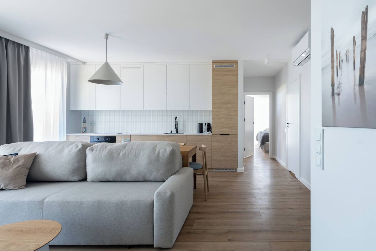 A modern kitchen with white cabinets, a wooden countertop, and a hanging light fixture.