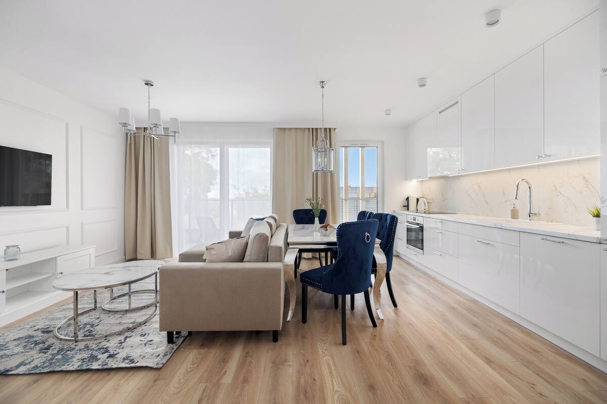A modern kitchen with white cabinets, a marble countertop, and a built-in oven.