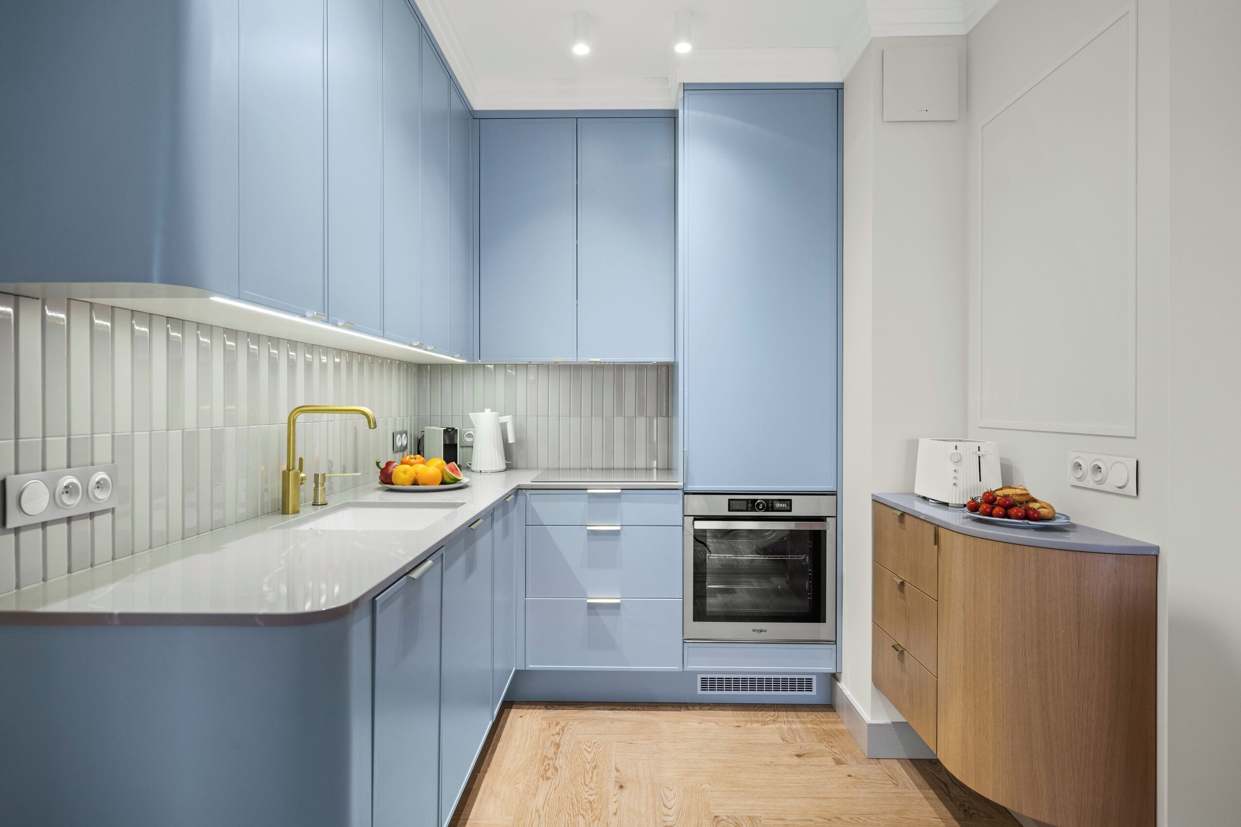 Una cocina moderna con armarios azul claro, encimera blanca y horno empotrado.