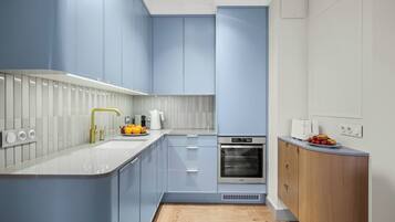 Una cocina moderna con armarios azul claro, encimera blanca y horno empotrado.