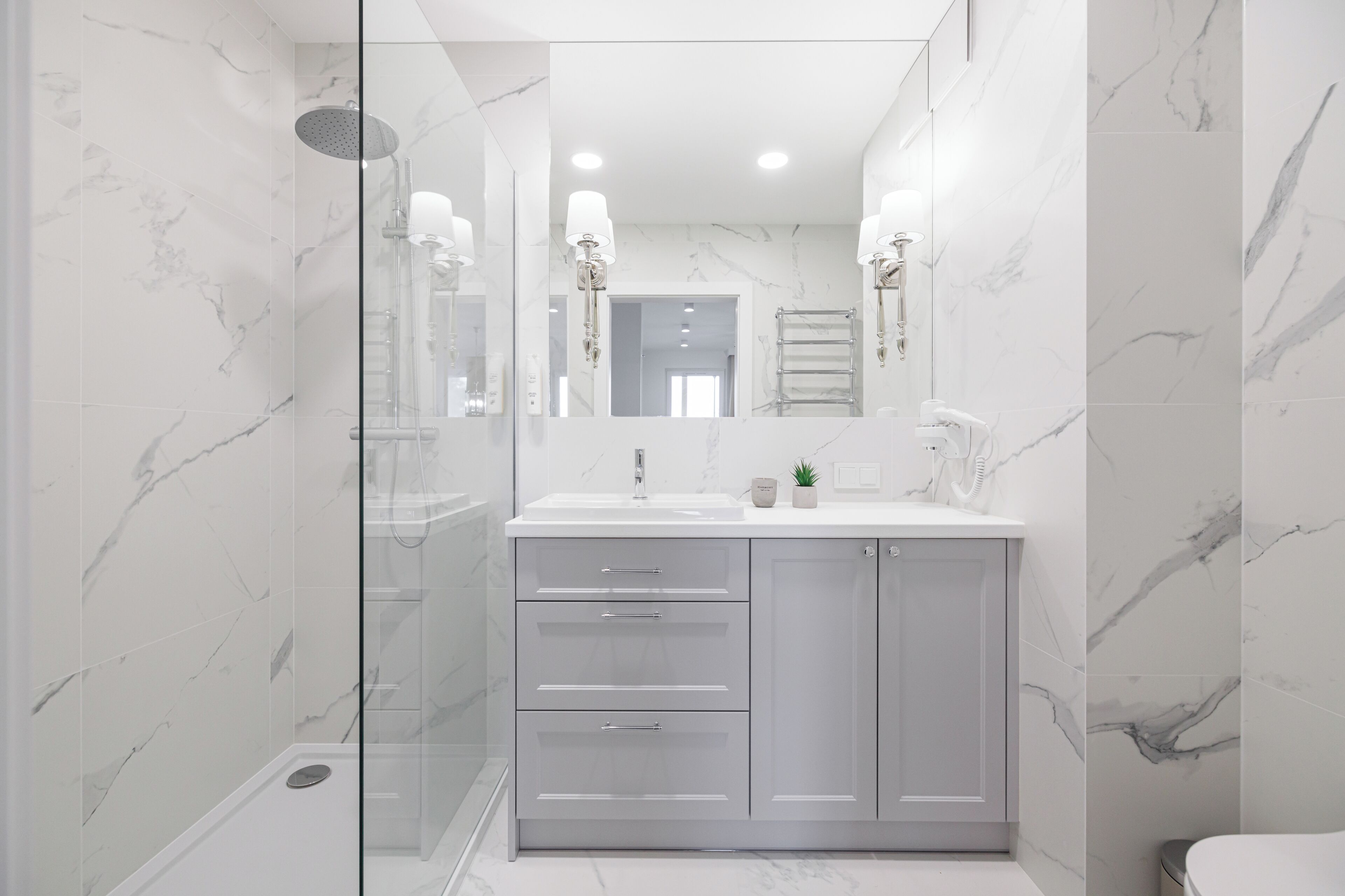 A modern bathroom with a glass shower enclosure, a vanity with a sink, and a mirror.