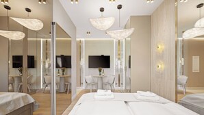 Een moderne hotelkamer met een groot bed, een zithoek met een tafel en stoelen, een televisie en een grote spiegel.