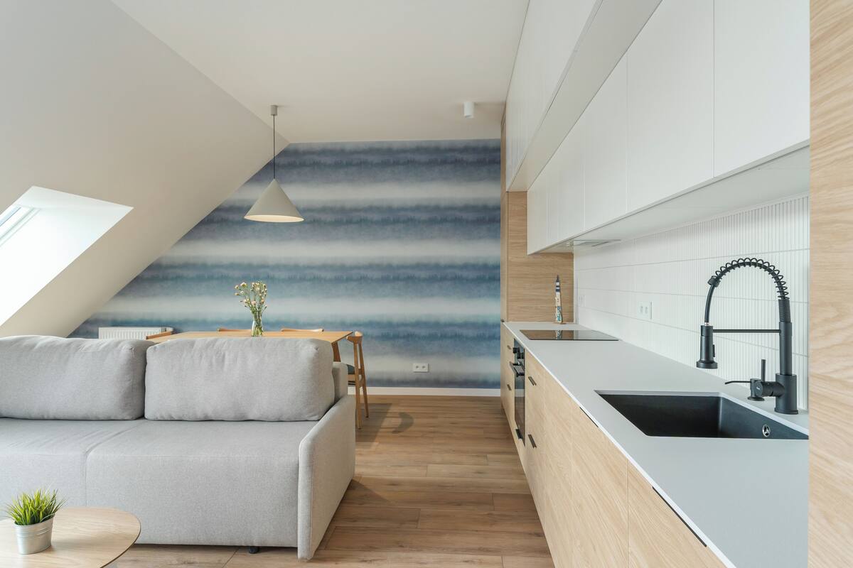 A modern kitchen with a built-in stove, a sink with a black faucet, and a wooden countertop.