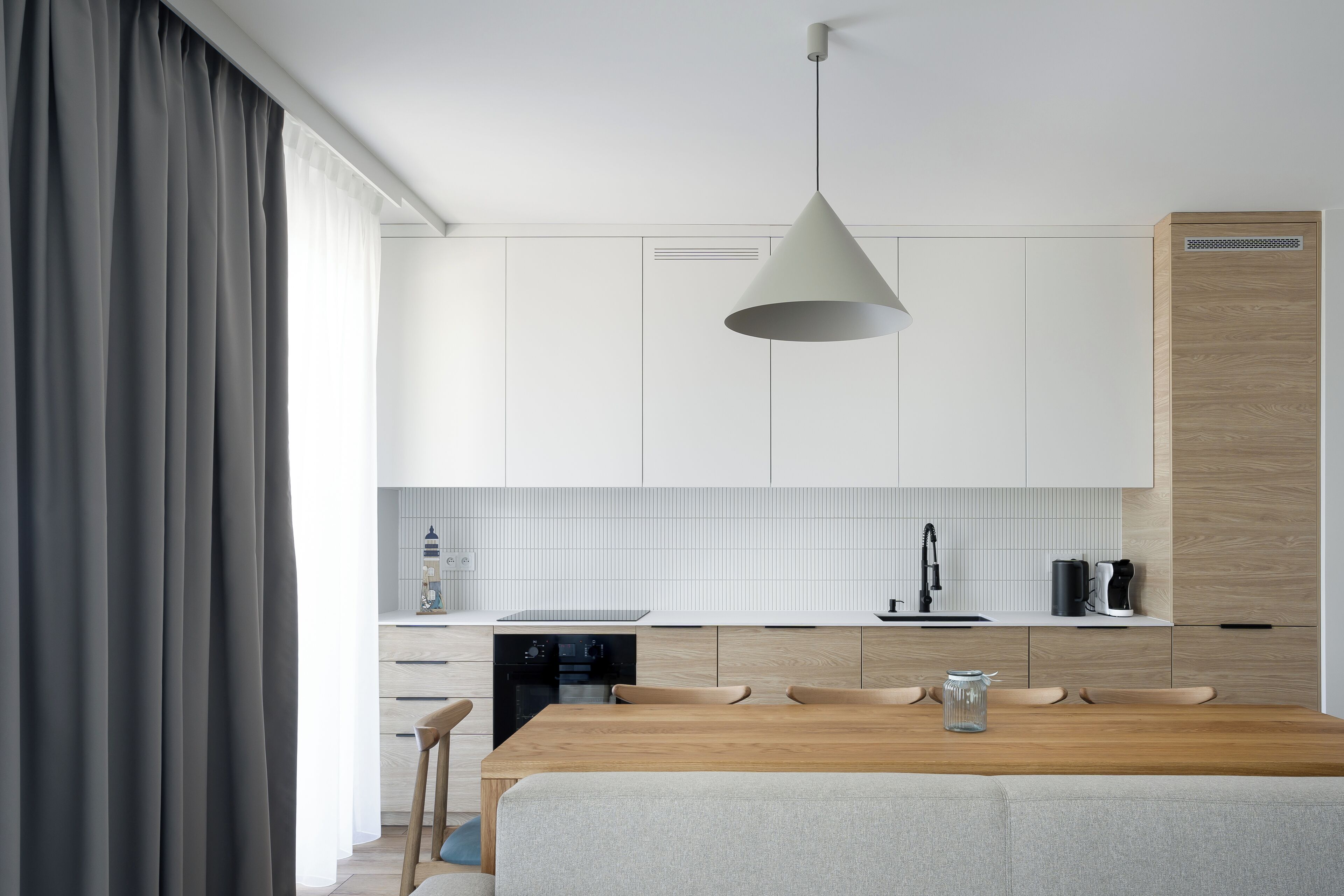 A modern kitchen with white cabinets, a wooden countertop, and a hanging light fixture.