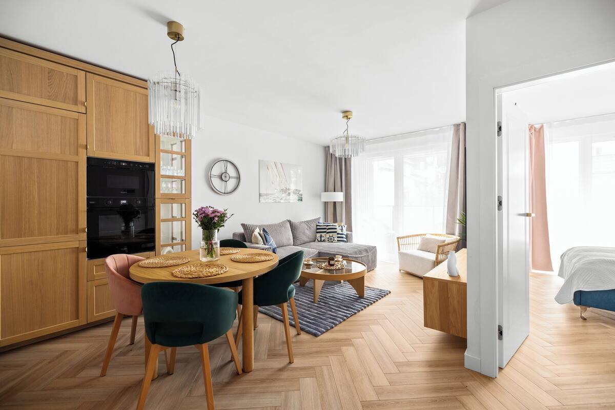 A modern kitchen with wooden cabinets, a dining table with chairs, and a chandelier.