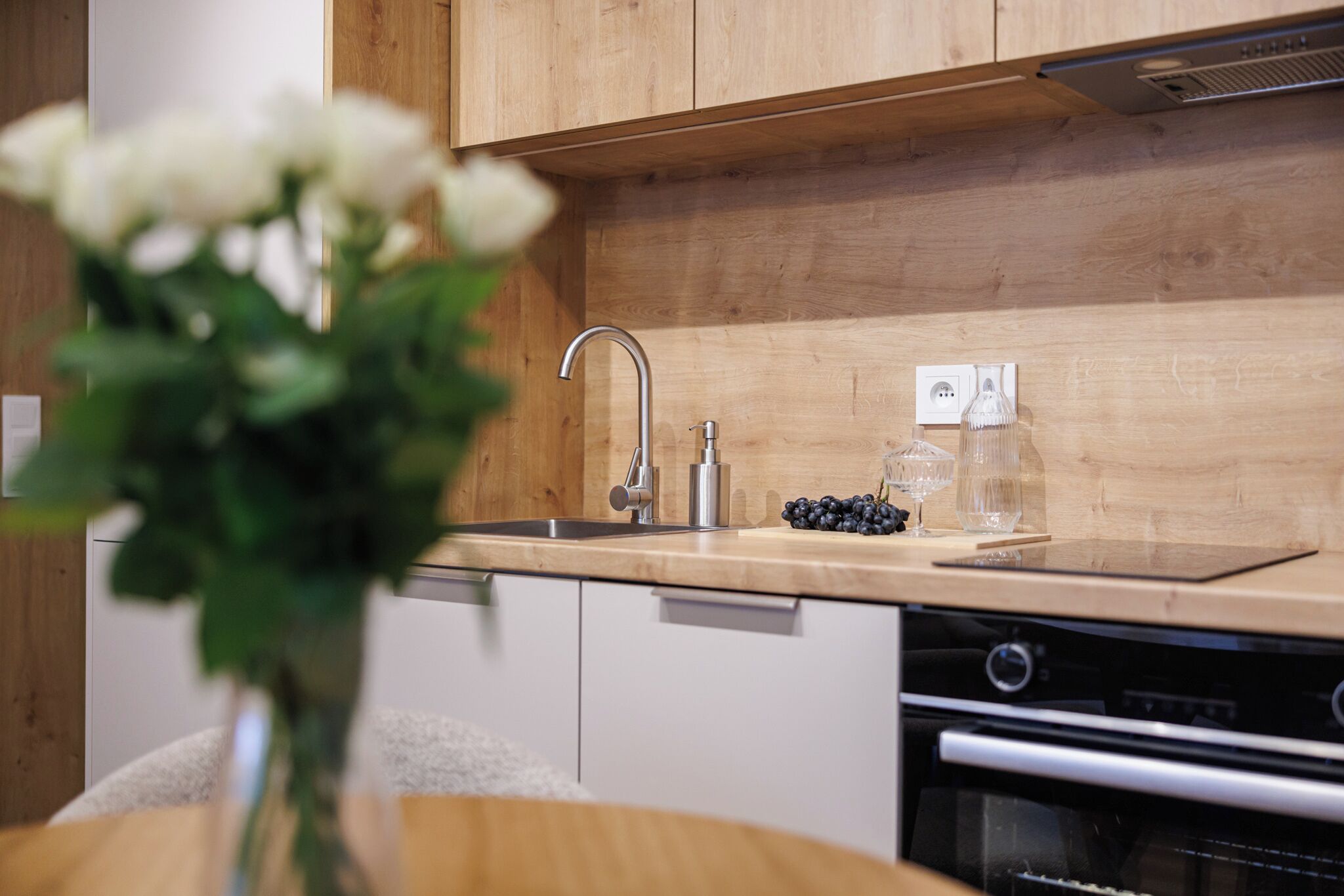 A modern kitchen with wooden cabinets, a stainless steel sink, and a built-in oven.