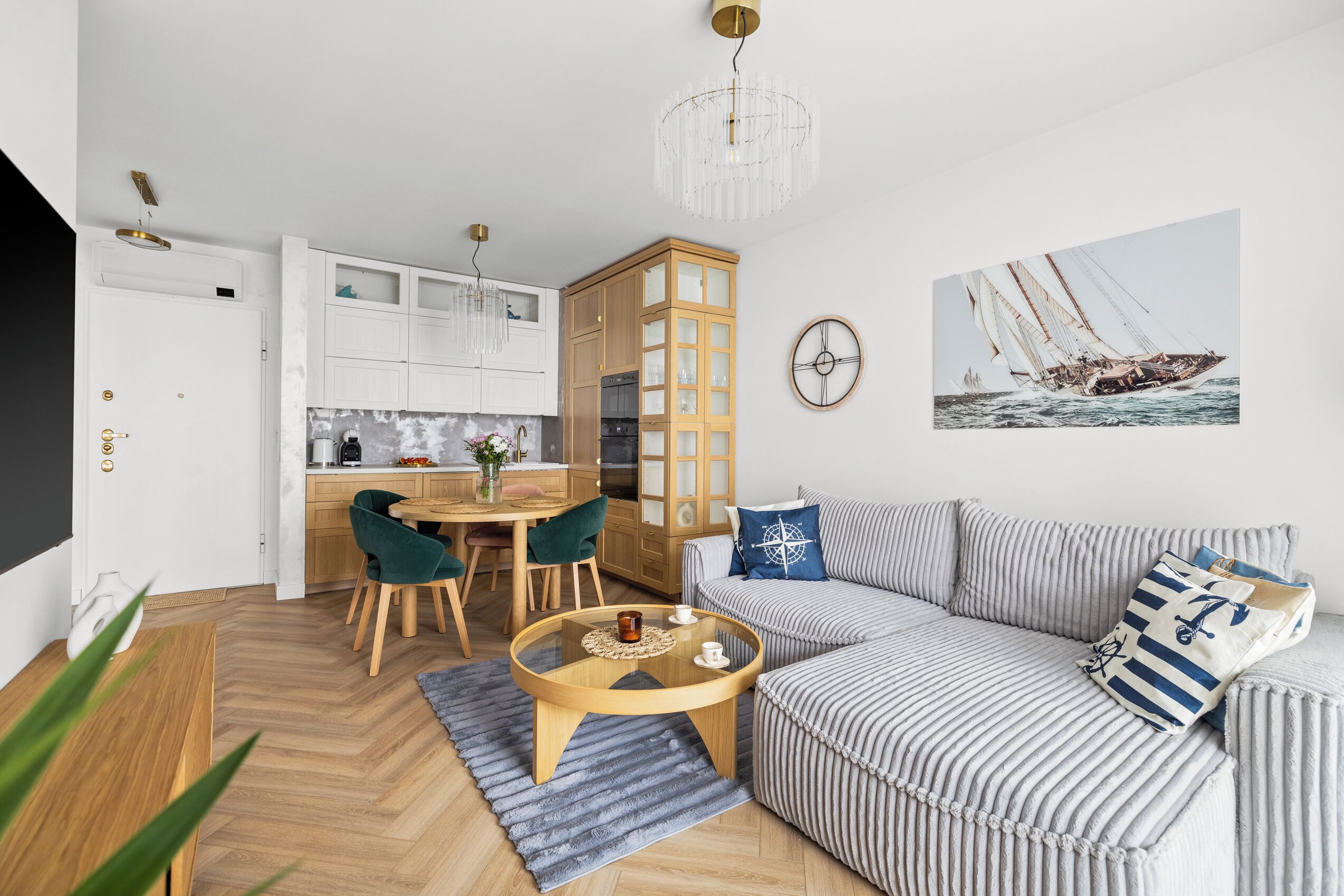 Un salon moderne avec un canapé à rayures, une table basse en bois et un coin repas comprenant un buffet en bois et des chaises.