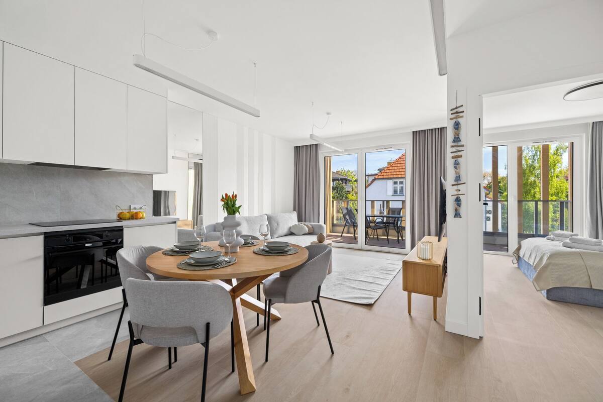 A modern, open-plan living space with a kitchen, dining area, and a bedroom.