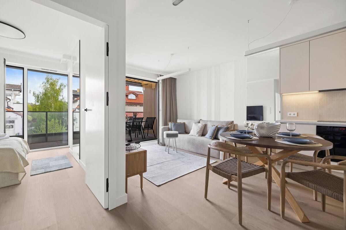 A modern living room with a dining area, a sofa, a coffee table, and a TV.
