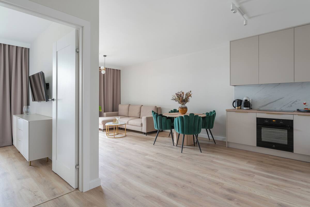 A modern kitchen with a marble countertop, a built-in oven, and a dining area with a round table and chairs.