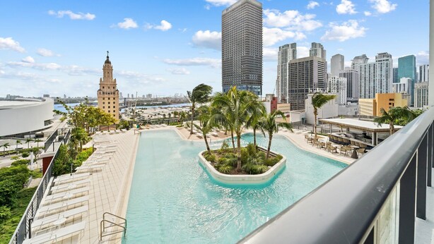 A rooftop pool with a view of a city skyline, including a prominent tower and modern buildings.
