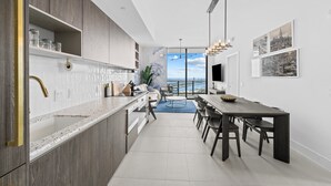 A modern kitchen with a large island, dark wood cabinets, and a view of the ocean.