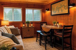 Ein gemütliches Blockhaus-Interieur mit Holzausstattung, einem Esstisch mit Stühlen, einer Couch und einer Karte an der Wand.