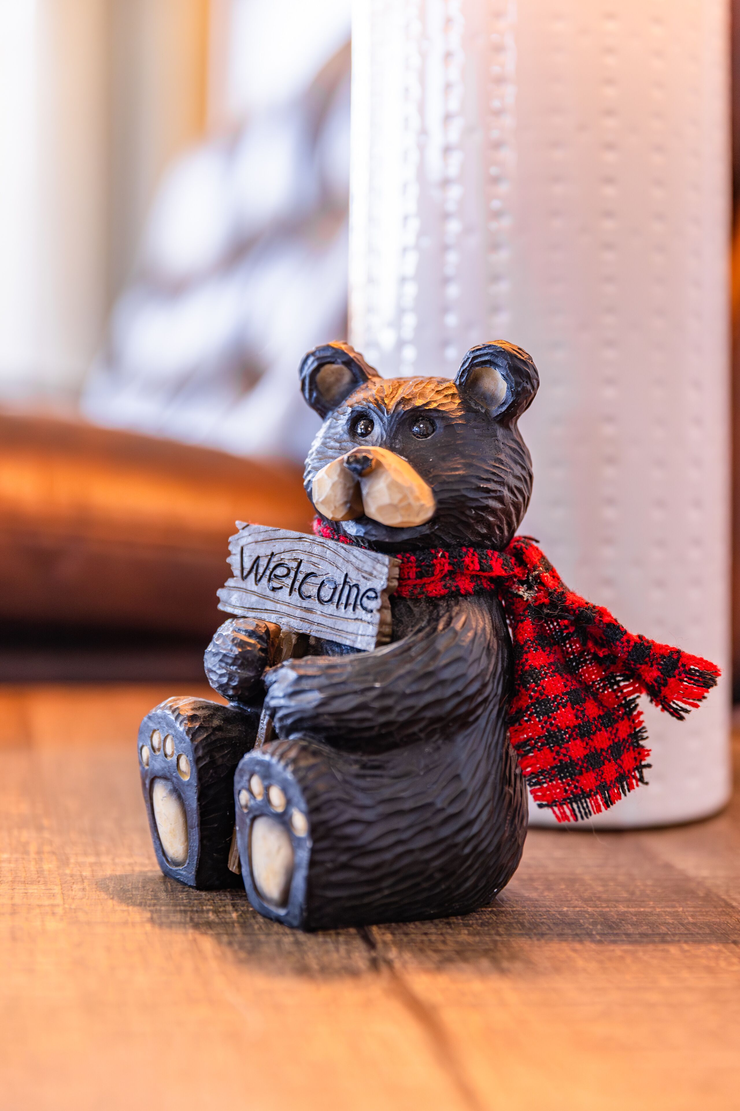 A small bear figurine holding a sign that says "Welcome".