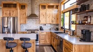 Une cuisine moderne avec des meubles en bois, des appareils électroménagers en acier inoxydable et une grande fenêtre qui laisse entrer la lumière naturelle.