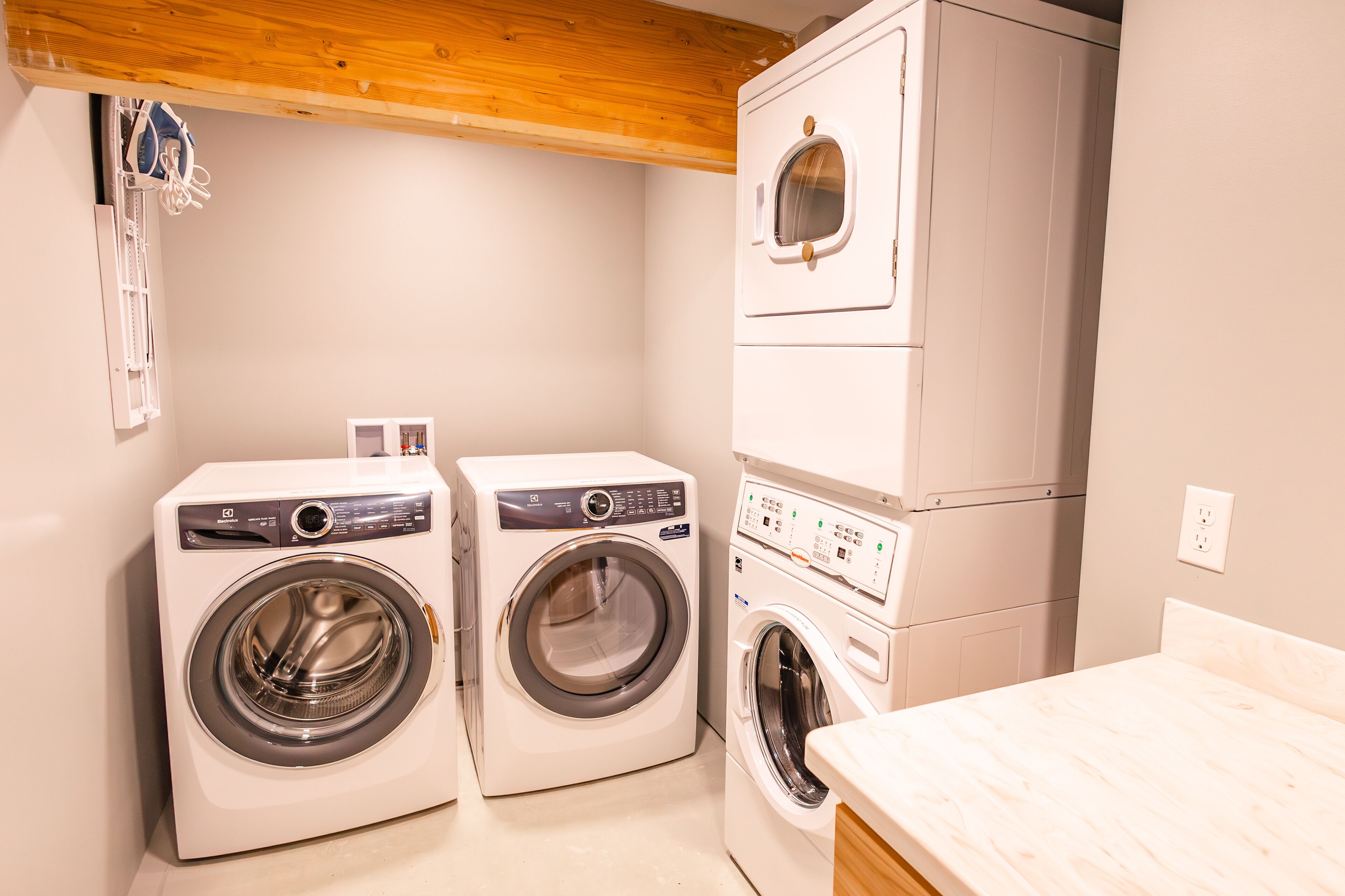 A laundry room with two front-loading washing machines and a stacked dryer.