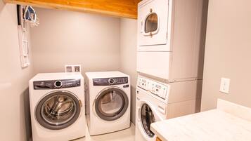 A laundry room with two front-loading washing machines and a stacked dryer.