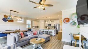 A spacious living area with a sectional sofa, a round coffee table, and a dining table.