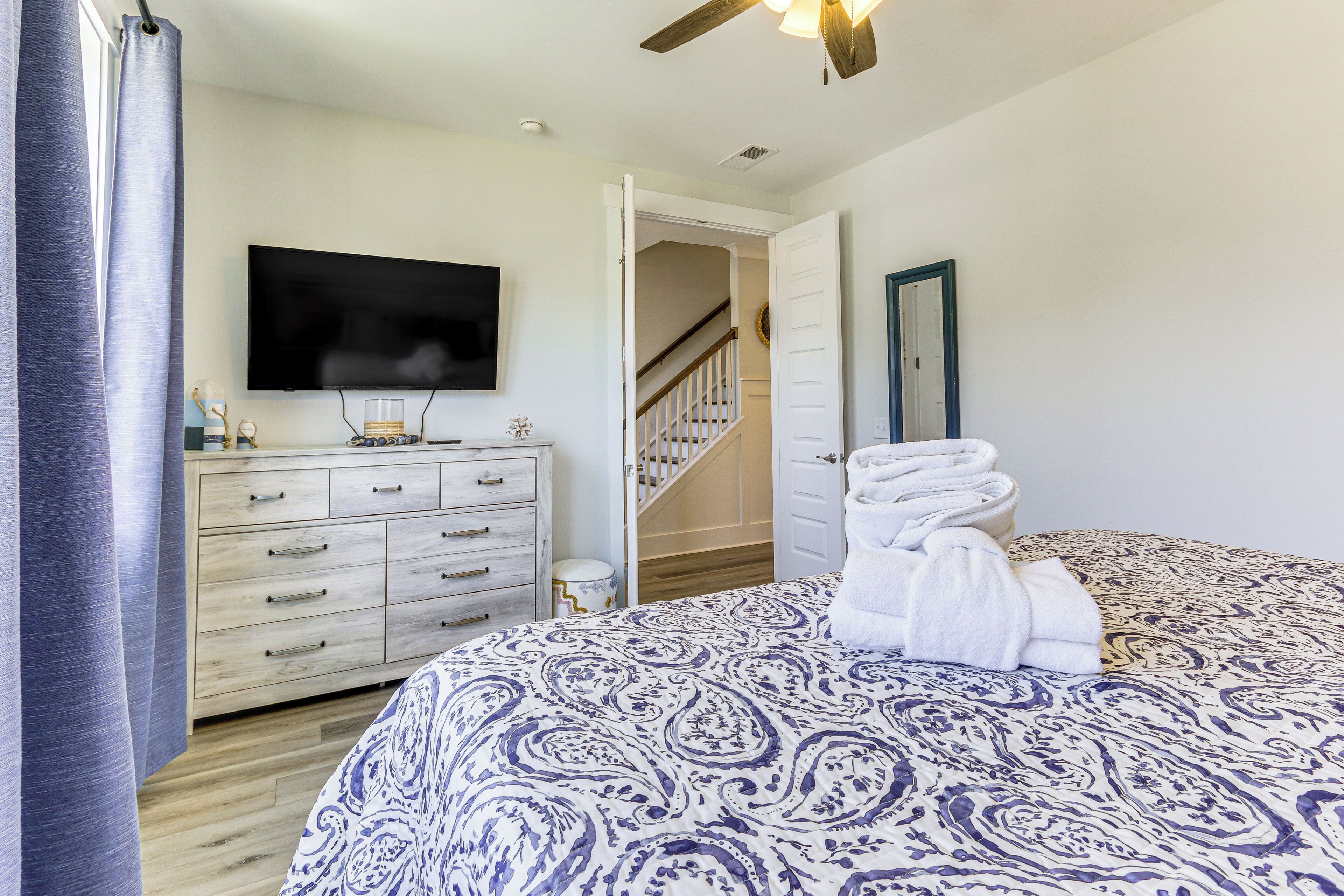 A bedroom with a bed, a dresser, a television, and a staircase leading to another room.