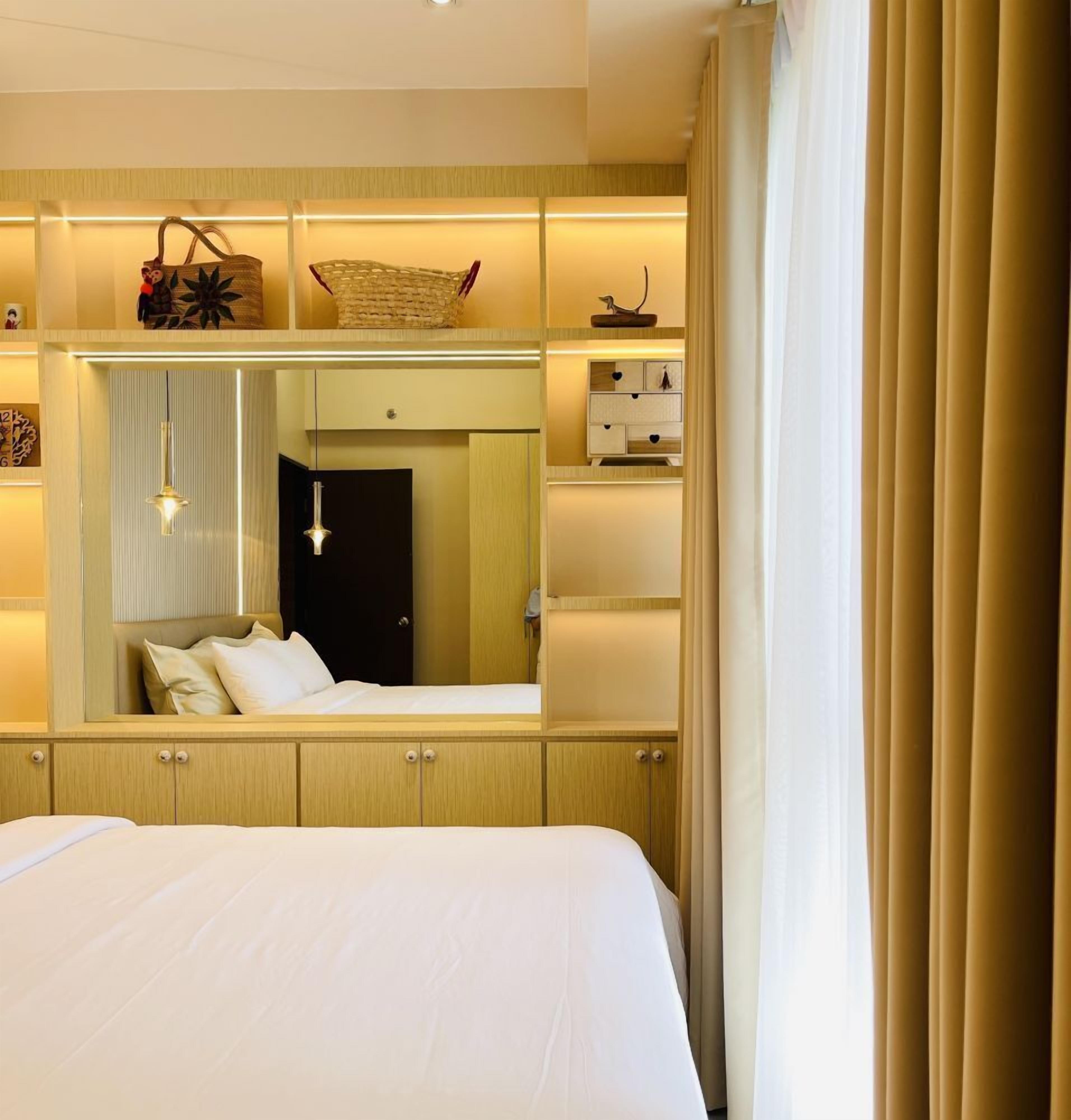 A hotel room with a large bed, a wardrobe, a mirror, and a bedside table.