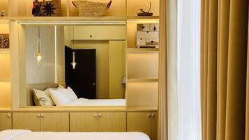 A hotel room with a large bed, a wardrobe, a mirror, and a bedside table.