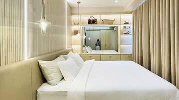 A modern bedroom with a large bed, bedside tables, a mirror, and a wardrobe.