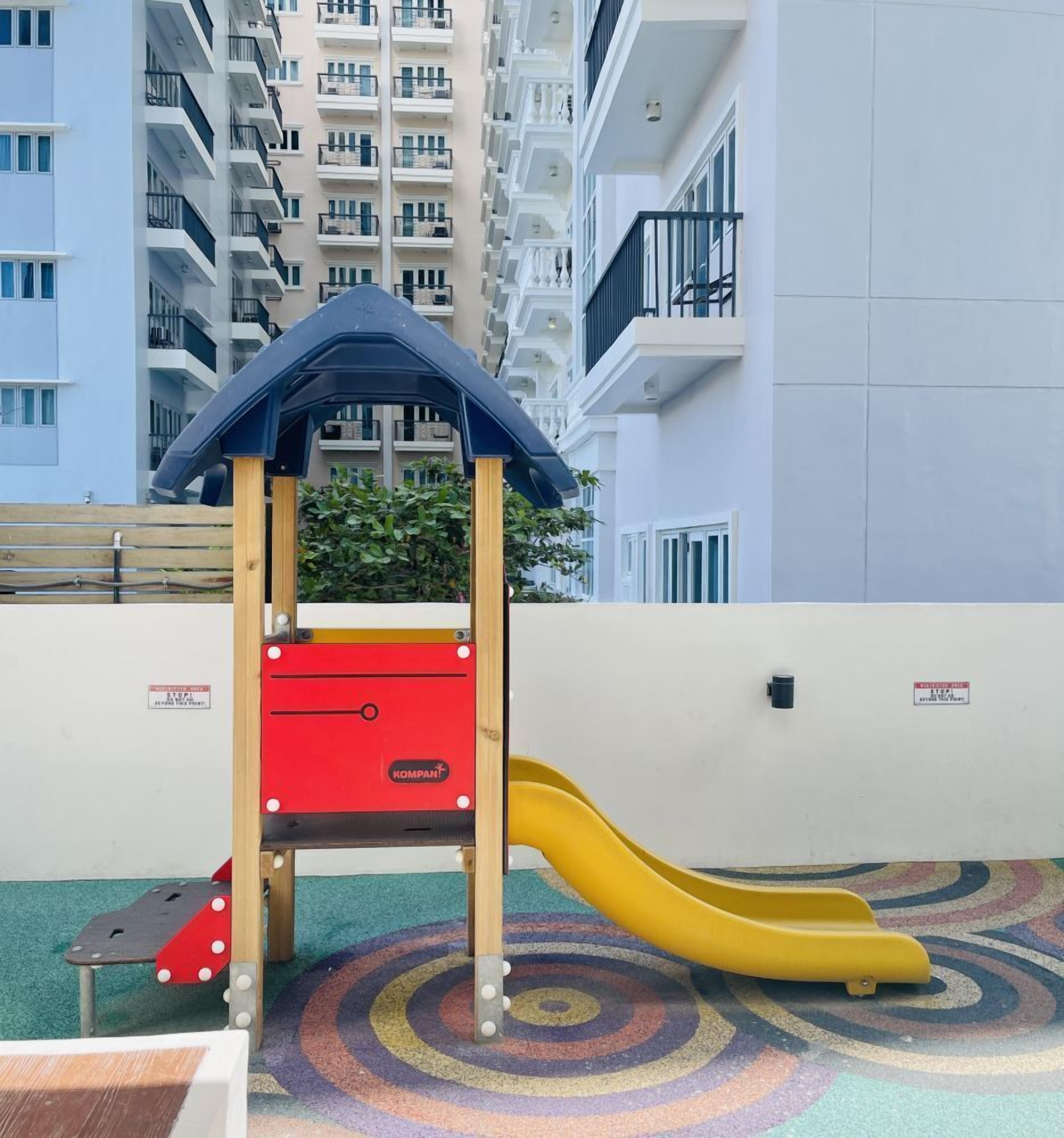 Parque infantil com escorrega e estrutura de escalada em ambiente urbano.