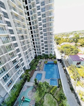 Residents enjoy a rooftop pool area with two pools and a children's play space.