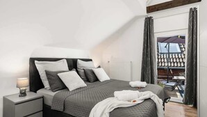 Ein modernes Schlafzimmer mit einem großen Bett, einem Nachttisch und Blick auf eine Terrass'.