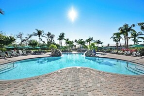 Piscina com espreguiçadeiras e palmeiras.