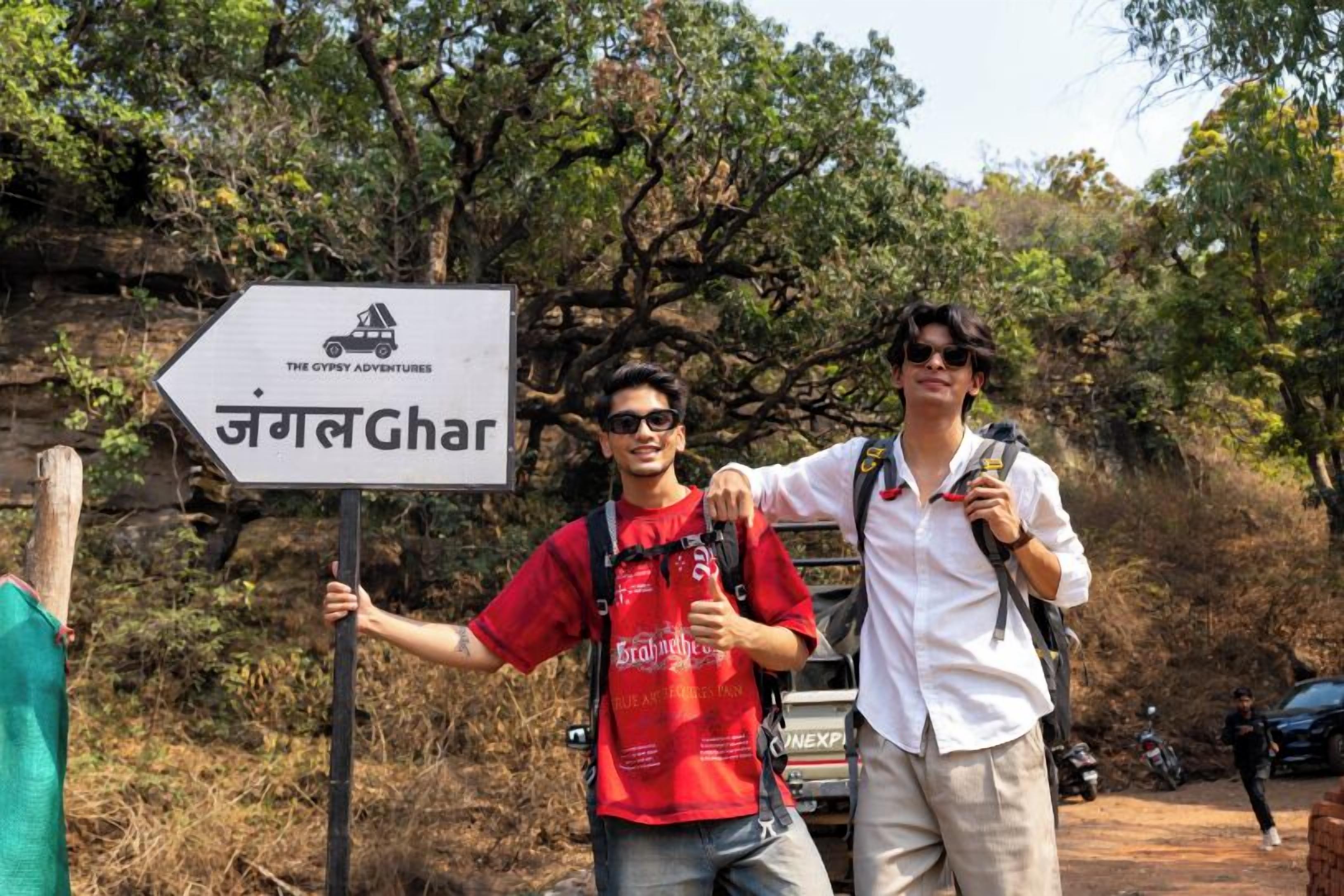 Two people standing next to a sign with text in a non-English language and a logo for 'The Gypsy Adventures'.