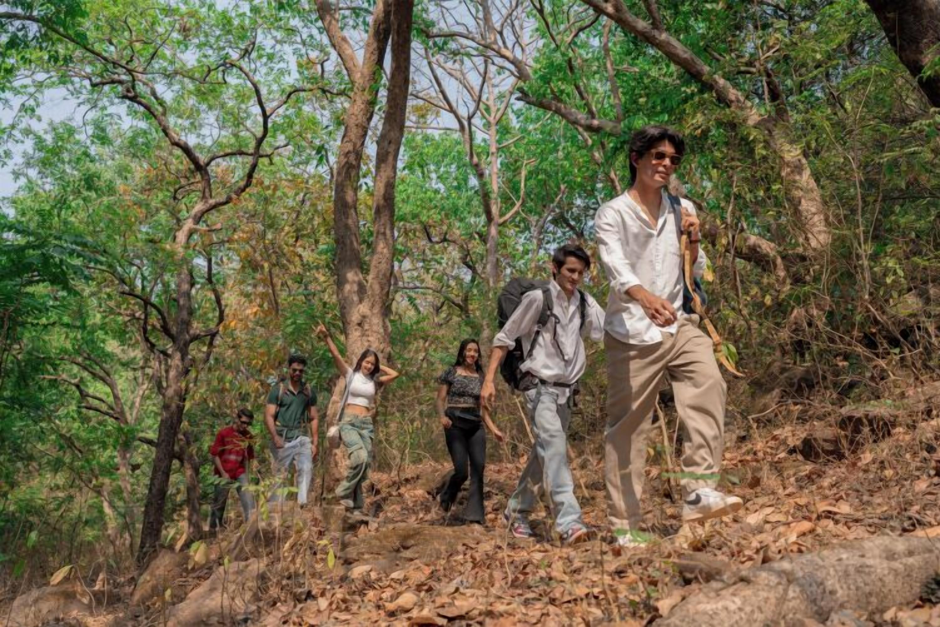 A group of people hiking in a forested area with trees and natural terrain.