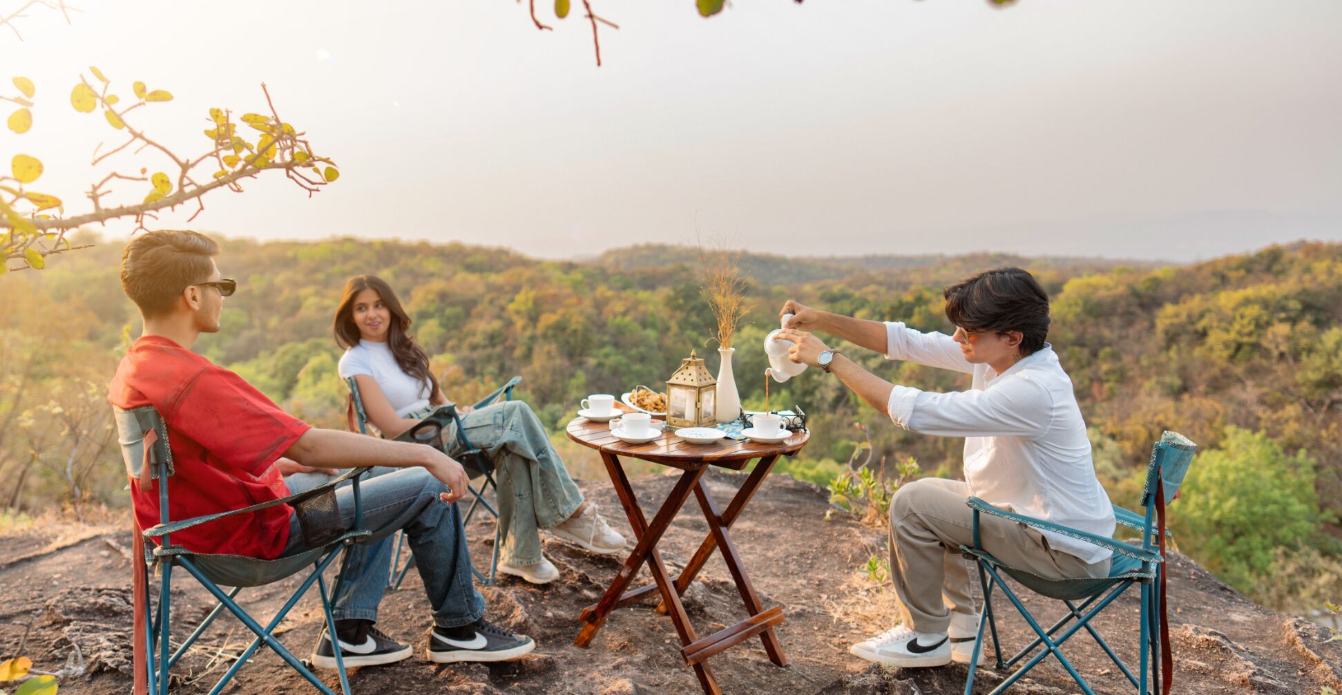 Tres personas sentadas en una mesa de madera al aire libre, con una vista panorámica al fondo.