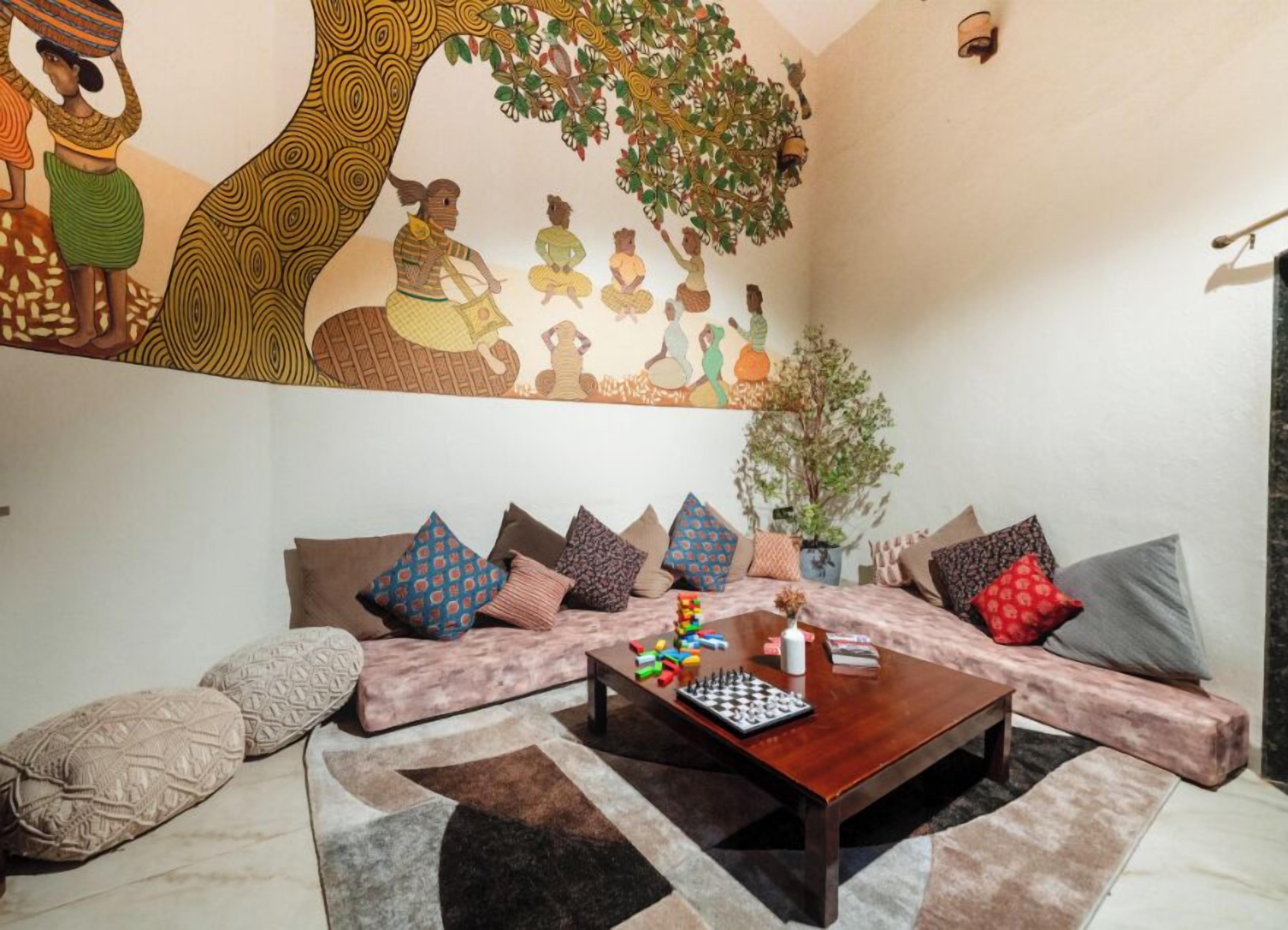 A living room with a sofa set, a coffee table with chess pieces, and a mural on the wall.