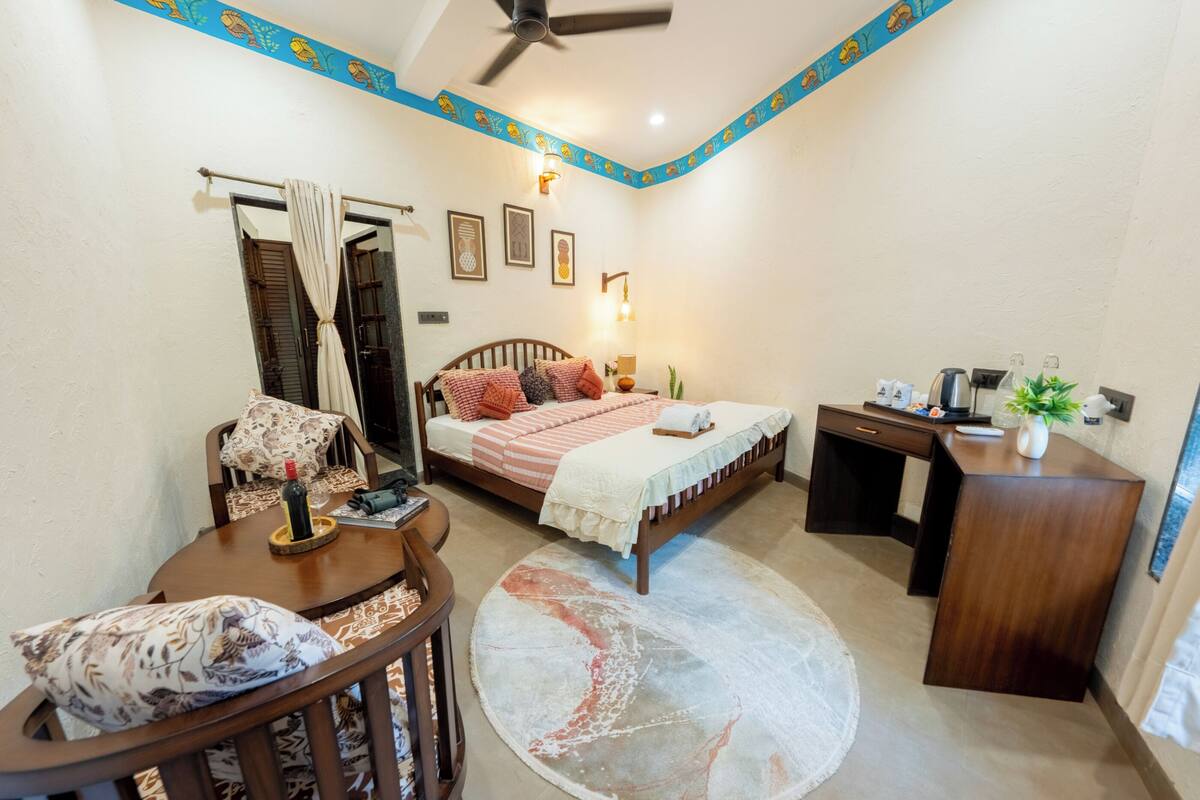 A bedroom with a bed, bedside table, desk, and chair.