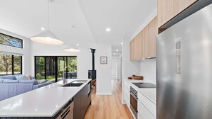 A modern kitchen with a central island, stainless steel appliances, and a view to the outdoors. - Tranquil at Rosedale (Rosedale)
