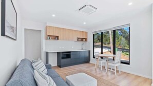 A modern kitchen with a dining area, a sofa, and a large window. - Tranquil at Rosedale (Rosedale)