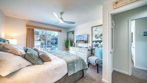 Une chambre à coucher avec un grand lit, une commode, un miroir et un ventilateur de plafond.