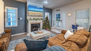 Un salon avec une cheminée, un sapin de Noël et une grande fenêtre donnant sur la plage.